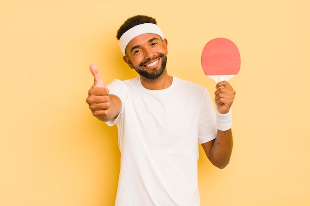 Schwarzer Afro-Mann fühlt sich stolz und lächelt positiv mit Daumen nach oben Pingpong-Konzept