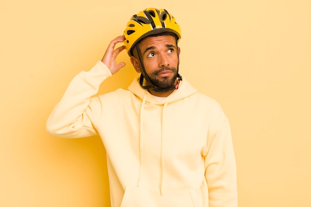 Schwarzer Afro-Mann lächelt glücklich und träumt oder zweifelt am Fahrradkonzept