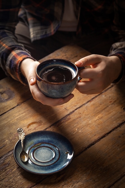 Schwarzer americano Kaffee in der blauen Schale in der männlichen Hand