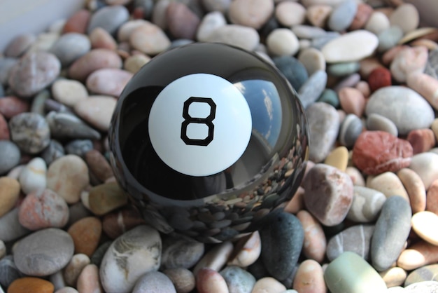 Foto schwarzer billardball nummer acht liegt auf einem farbigen glatten kies top view