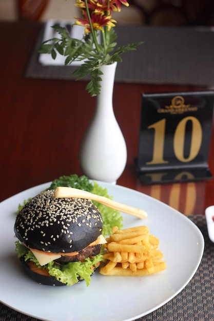 Schwarzer Burger mit gebratenem Pommes-Hintergrund