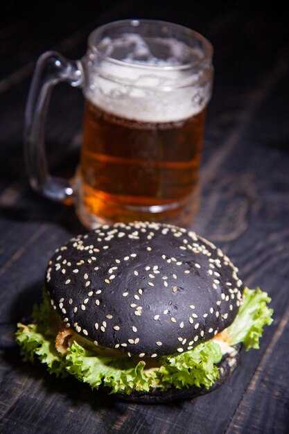 Schwarzer Burger und Glas Bier einzeln auf Schwarz. Weicher Fokus. selektiver Fokus.