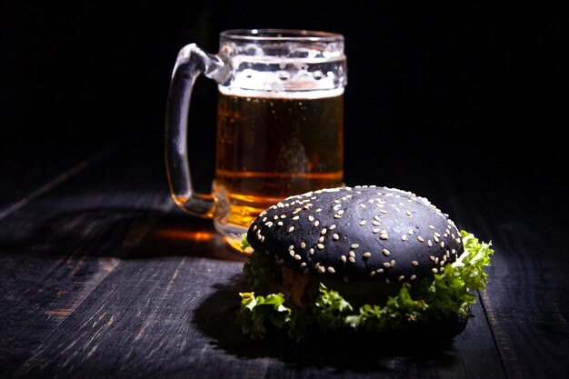 Schwarzer Burger und Glas Bier einzeln auf Schwarz. Weicher Fokus. selektiver Fokus.