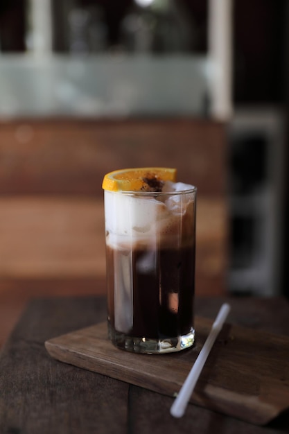 Schwarzer Eiskaffee mit Orange auf Holzhintergrund