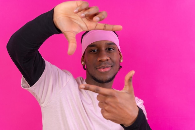 Schwarzer ethnischer Mann in rosafarbener Kleidung auf einem rosa Hintergrundkonzeptporträt lächelnd