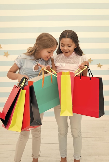 Foto schwarzer freitag auf dem schulmarkt, glückliche kleine kinder, mädchen mit einkaufstaschen nach dem verkauf am schwarzen freitag, kleine kinder mit einkäufen vom schulmarkt