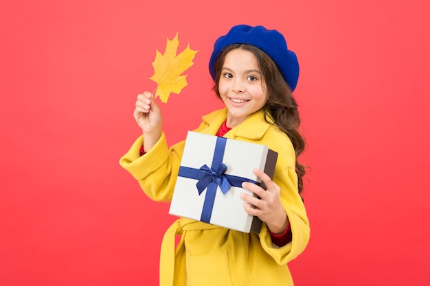 Schwarzer Freitag Kleines Mädchen Herbst-Outfit roter Hintergrund Kleines Mädchen und Geschenkbox Kind halten Herbstahornblatt Kind bekam Geschenk Herbst-Shopping Saisonverkauf Mit Dank erhalten Geschenke des Herbstes