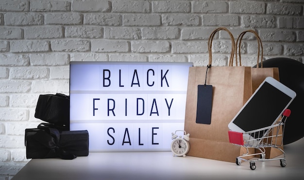 Schwarzer Freitag Verkaufswörter auf Lightbox mit schwarzem Preisschild und Geschenken Frontansicht