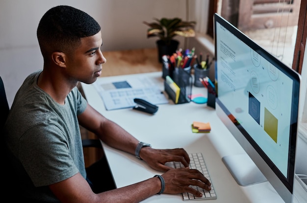 Schwarzer Geschäftsmann oder Grafikdesigner schreibt auf dem Computer für das Logo-Design bei einem kreativen Startup Tastaturmonitor oder Künstler arbeitet an einem Projekt für die Bearbeitung der Markenidentität oder die Social-Media-Planung