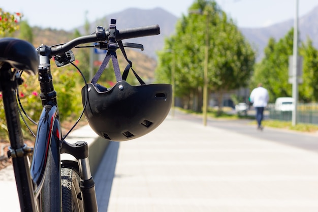 Schwarzer Helm am Fahrradlenker auf der Straße an einem sonnigen Tag Sicherheitskonzept