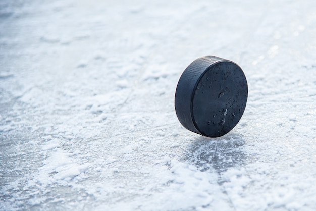 Schwarzer Hockey-Puck liegt auf Eis im Stadion