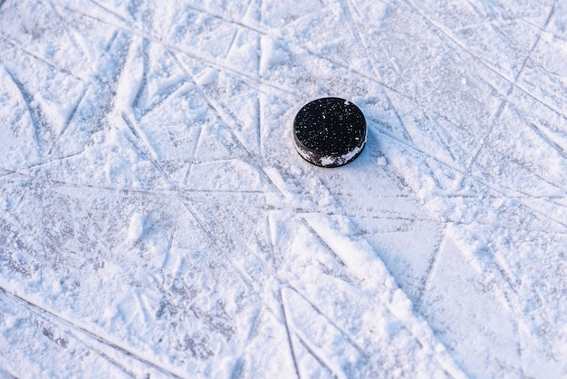 Schwarzer Hockey-Puck liegt auf Eis im Stadion