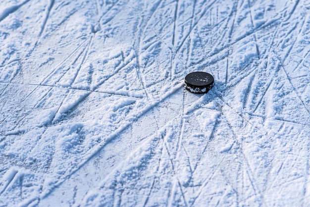 Schwarzer Hockey-Puck liegt auf Eis im Stadion