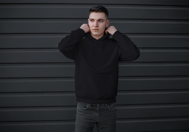 Foto schwarzer hoodie mit einer tasche an einem jungen mann in jeans-vorderansicht langarm-sweatshirt