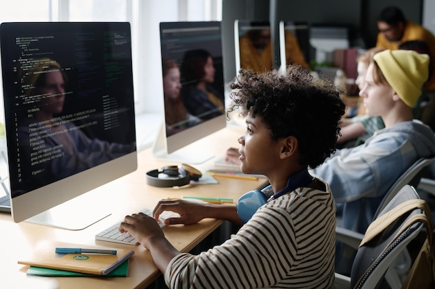 Schwarzer Junge programmiert im Unterricht am Computer