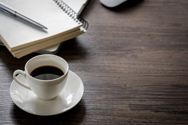 Schwarzer Kaffee auf der Schreibtischtabelle mit Computer, silberner Stift