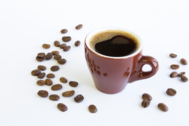 Schwarzer Kaffee in der braunen Tasse und Kaffeebohnen auf dem weißen Hintergrund Nahaufnahme