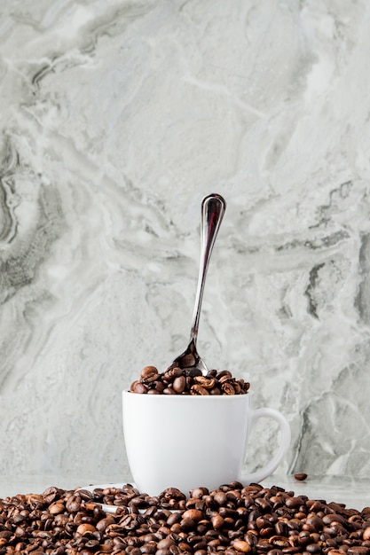 Schwarzer Kaffee in der Schale und in den Kaffeebohnen auf Marmorhintergrund.