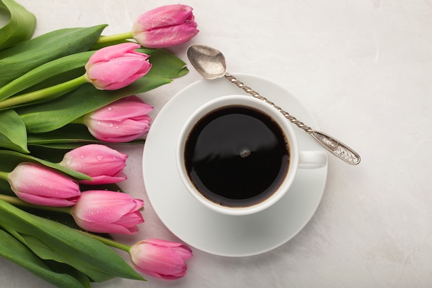 Schwarzer Kaffee in der weißen Schale und in den Tulpen.