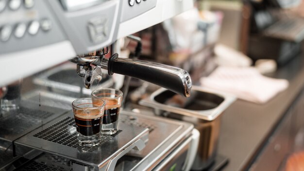 schwarzer Kaffee in Messbecher auf Kaffeemaschine setzen