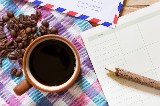 Schwarzer Kaffee und Briefpapier und ein Bleistift auf einem Holztisch