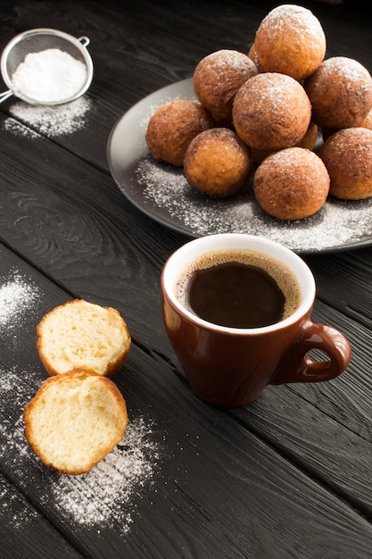 Schwarzer Kaffee und hausgemachte Hüttenkäse-Donuts im Dunkeln