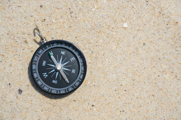 Foto schwarzer kompass auf dem strandsand