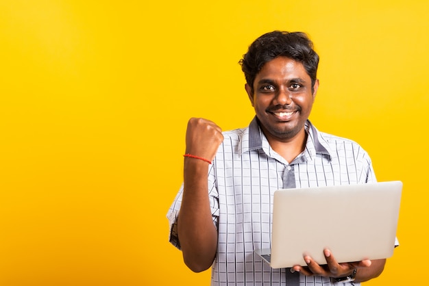 Schwarzer Mann aufgeregt hält Laptop Computer geballte Fäuste und hebt eine Hand für den Gewinner