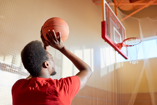 Schwarzer Mann, der Basketballball wirft