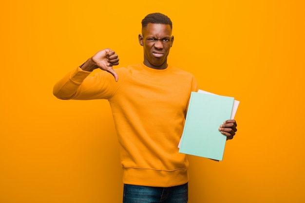 Schwarzer Mann des jungen Afroamerikaners gegen orange Wand mit einem Buch