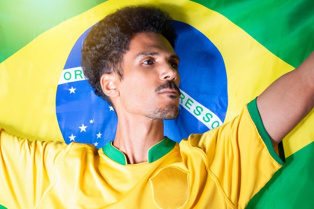 Foto schwarzer mann mit brasilianischer flagge hinter dem feiern