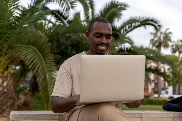 Schwarzer Mann mit Netbook im Park