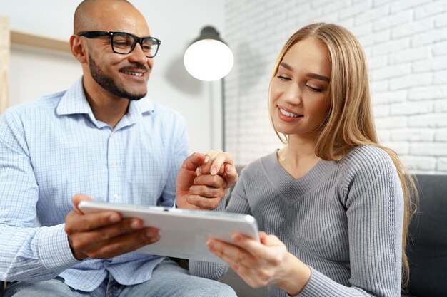 Schwarzer Mann und kaukasische Frau schauen sich gemeinsam etwas auf einem digitalen Tablet an