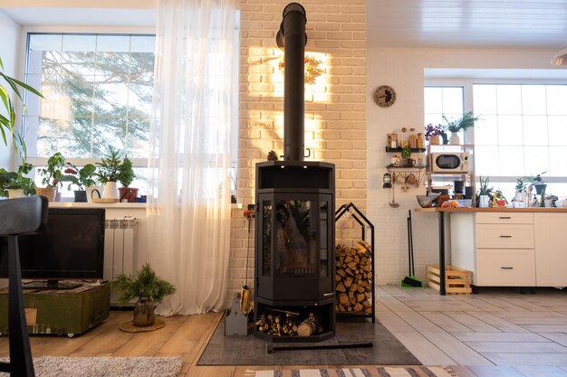 Schwarzer Ofenkamin im Inneren des Hauses im Loft-Stil Alternative umweltfreundliche Heizung warmes, gemütliches Zimmer zu Hause, das Holz verbrennt