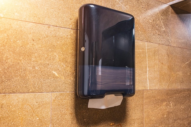 Foto schwarzer papierhandtuchspender an der wand in einer öffentlichen toilette