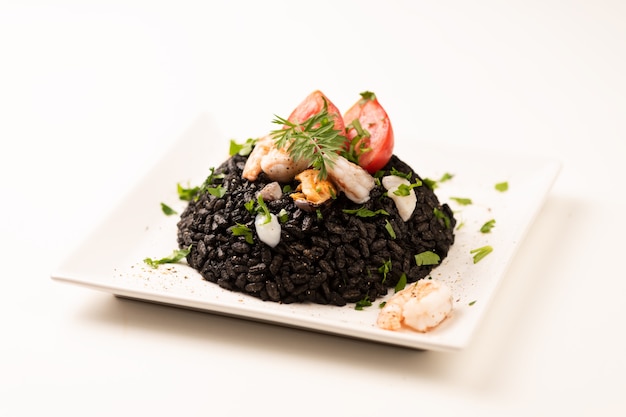 Schwarzer Reis mit Tintenfisch auf weißem Hintergrund Nahaufnahme