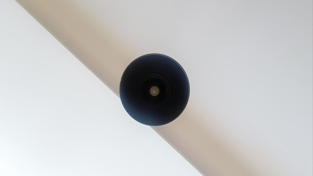 Schwarzer runder Deckenleuchter oder Lampe, die weiß von der Decke hängt. Unteransicht einer Glühbirne. Architektonische Dekoration an der Decke, hängender runder Kronleuchter. Minimalismus.