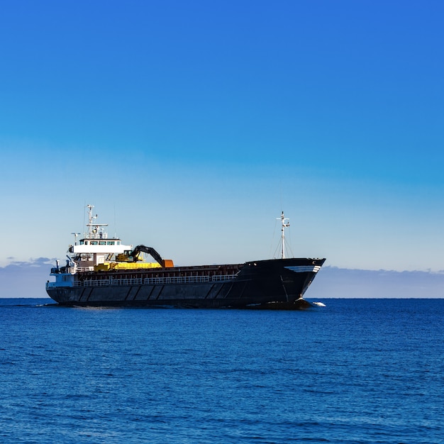 Schwarzer Segel-Massengutfrachter. Frachtschiff mit Bagger mit großer Reichweite, der sich im stillen Wasser am sonnigen Tag durch das Meer bewegt