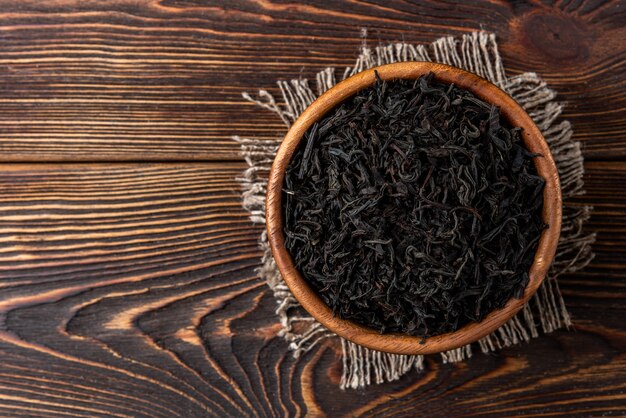 Schwarzer Tee auf dunklem hölzernem Hintergrund.