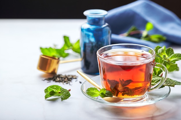 Schwarzer Tee im transparenten Glasbecher mit Minzblättern beruhigender Tee Antistress