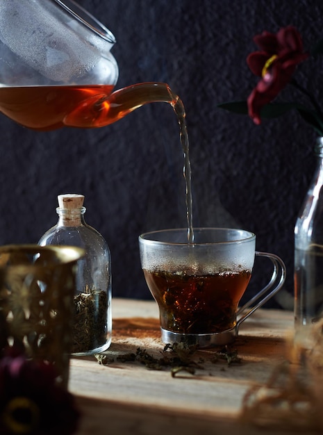 Schwarzer Tee wird aus einem Teekannchen in eine Tasse gegossen