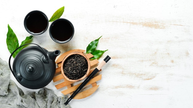 Schwarzer traditioneller Tee in einer Tasse mit Wasserkocher Auf weißem Holzhintergrund Draufsicht freier Platz für Ihren Text