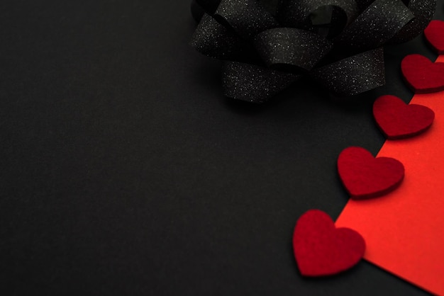 Schwarzer und roter Hintergrund, verziert mit einer schwarzen Schleife und roten Herzen, einem Banner für Rabatte oder Congra