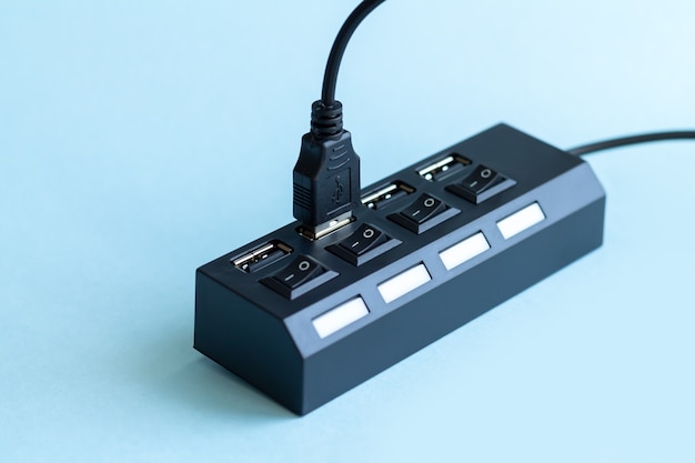 Schwarzer USB-Hub mit USB-Kabelstecker auf hellblauer Oberfläche