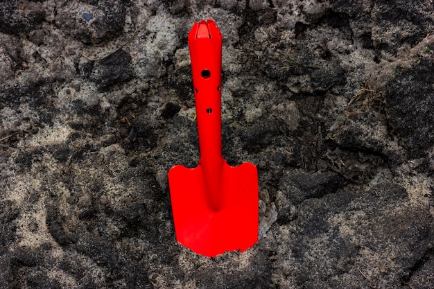 Foto schwarzerdebearbeitung mit einer gartenkelle ein roter gartenspachtel ragt aus der schwarzen erde