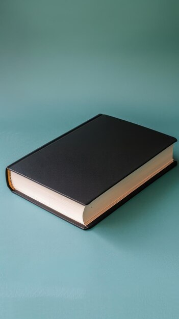 Schwarzes Buch mit leerem Cover auf türkisfarbenem Hintergrund Bildung oder religiöses Konzept