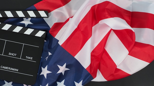 Schwarzes Clapper Board oder Filmschiefer und Flagge der Vereinigten Staaten von Amerika (USA.) auf schwarzem Hintergrund.