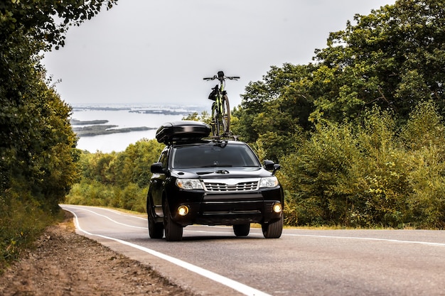 Schwarzes Crossover mit Fahrrad und Dachbox am Dachträger