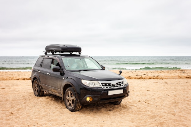 Schwarzes Crossover mit Kofferraum am Sandstrand im Sommer