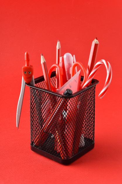 Schwarzes Metallglas mit roten Stiften, Farben und Bleistiften auf rotem Hintergrund Schule liefert Platz zum Kopieren